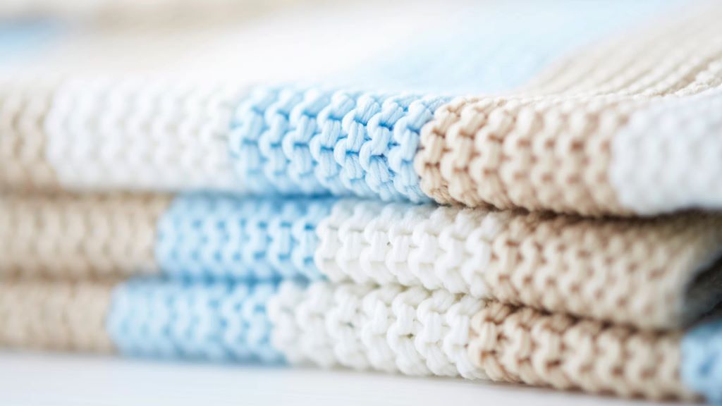 Soft pastel baby blanket knitted with organic cotton yarn.