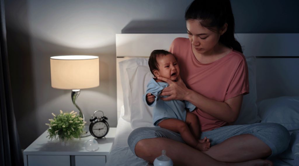 Close-up of a parent making a shushing sound to calm a fussy baby in a cozy nursery