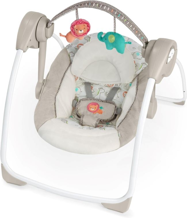 Baby resting in the Ingenuity Soothe ’n Delight Compact Portable Swing, Cozy Kingdom design